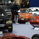 A photo of two people talking next to a car on display at an auto show.
